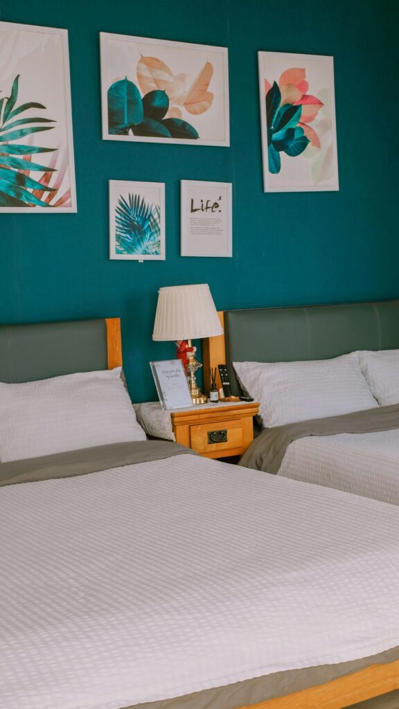 Two beds against a deep teal wall