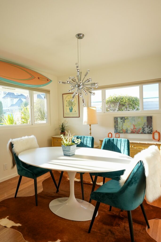 Dining nook with teal chairs and a surfboard