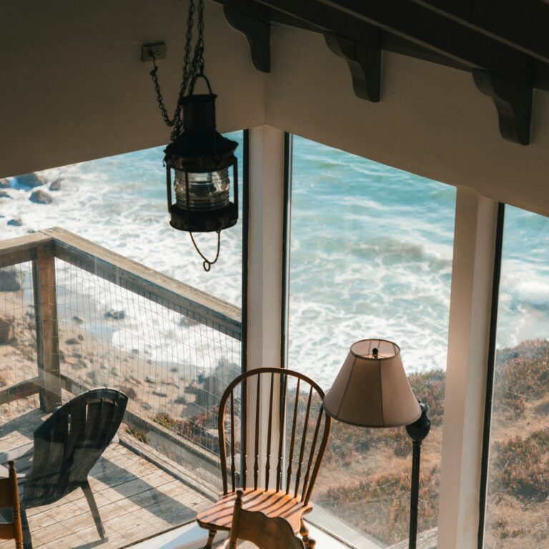 A balcony chair and lantern looking out over the water